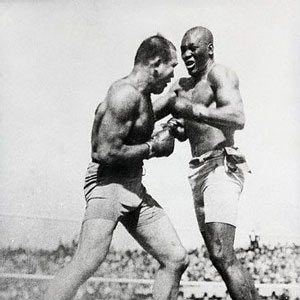 John Arthur ("Jack") Johnson, an American boxer at the height of the Jim Crow era, Johnson became the first African-American world heavyweight boxing champion of the world from 1908–1915. In this photo, Johnson is fighting James Jefferies, and Ken Burns noted that, "for more than thirteen years, Jack Johnson was the most famous and the most notorious African-American on Earth." Photo Credit: Wikipedia
