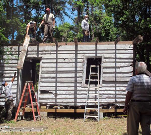 In this Monday, May 13, 2013 photo, workers remove roofing from a slave cabin on Edisto Island, S.C., to ship it to the Smithsonian National Museum of African American History and Culture, for display in 2015. Photo Credit: Bruce Smith